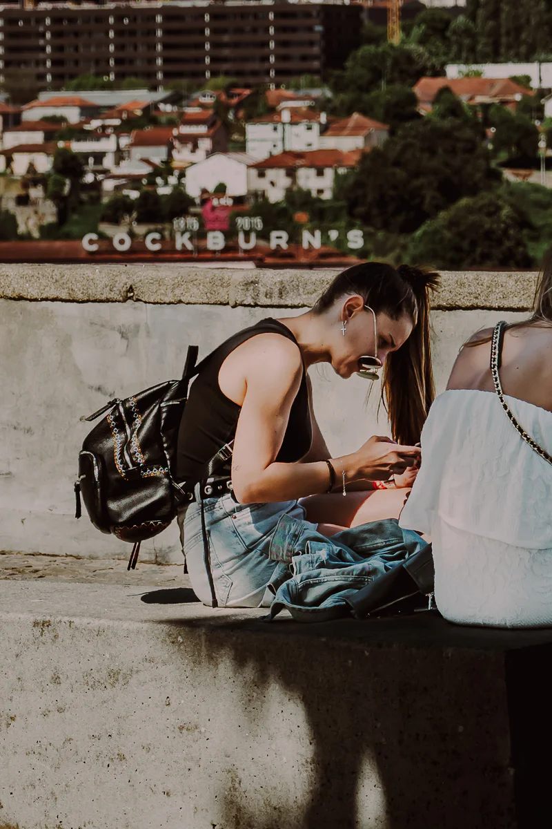 Young woman looking at phone near urban graffiti wall (Noor naine vaatab telefoni, taustal grafitiga sein)