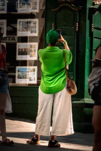 Woman in bright green shirt taking photo of real estate window in Porto (Naine eredas rohelises pluusis pildistab kinnisvaravitriini Portos)