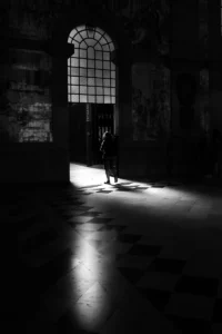 Figure entering bright doorway in large hall, dramatic light and shadow (Inimene astub valgusesse suure ukse kaudu, dramaatiline valgus ja vari)