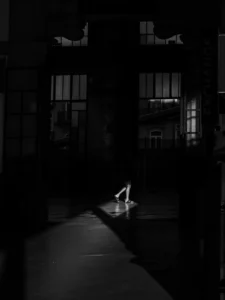 Legs of a person illuminated by a narrow beam of light in dark interior, black and white (Valgusvihus valgustatud inimese jalad pimedas interjööris, mustvalge kompositsioon)