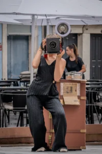 Woman holding a vintage box camera in front of a café in Porto (Naine retrokaameraga kohviku ees Portos, hetk jäädvustatud)
