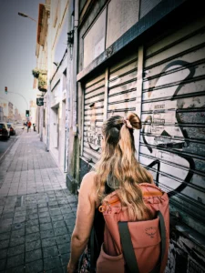Woman with backpack walking past graffiti-covered shutters in Porto (Naine seljakotiga jalutamas mööda Porto graffitiseina)