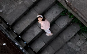 Little girl looking up while standing on stone stairs in Porto (Väike tüdruk kivitreppidel Portos, vaatab üles linnulennult)