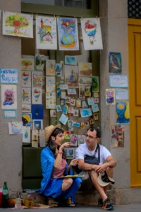Couple chatting in front of colorful postcard wall (Paar vestleb värviliste kunstikaartide ees)