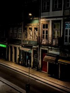 Nighttime street in Porto with abandoned shops and fading lamplight (Öine Porto tänav, suletud ärid ja hajuv tänavavalgus)