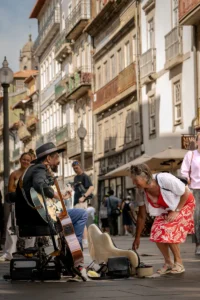 Guitarist performing for passersby on a cobbled street in Porto (Kitarrist esineb möödujatele Porto munakivitänaval)