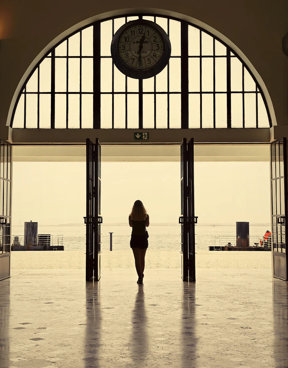 Person walking through Porto railway station’s main hall toward light (Inimene kõnnib Porto rongijaama peasaalis valguse suunas)