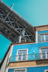Blue house beneath metal bridge structure in Porto riverside area (Sinine hoone metallist silla all Porto jõeäärses piirkonnas)