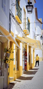 Bright yellow awnings on narrow Evora street, person walking in distance (Kollased varikatused Evora tänaval, kauguses kõndiv inimene)