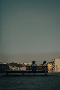 Couple sitting on bench overlooking Porto skyline in soft evening light (Paar istub pingil, taustal Porto panoraam pehme õhtuvalguse käes)