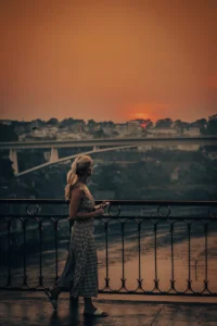 Woman standing by railing overlooking bridge and Douro River at sunset in Porto (Naine seisab piirde juures, taustal sild ja Douro jõgi päikeseloojangul Portos)