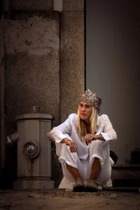 Woman in white outfit with crown sitting on city street in Porto (Naine valges riietuses ja krooniga istub Porto tänaval)
