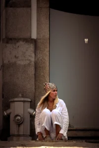 Woman in white outfit with crown sitting on city street in Porto (Naine valges riietuses ja krooniga istub Porto tänaval)
