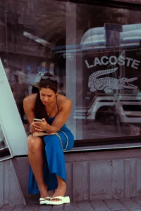 Woman in blue dress sitting by Lacoste store window reflection in Porto (Naine sinises kleidis istumas, peegeldus Lacoste poe aknas Portos)