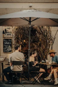 People sitting at outdoor café in Porto with lush greenery wall (Inimesed istuvad Porto välikohvikus, taustaks roheline taimesein)