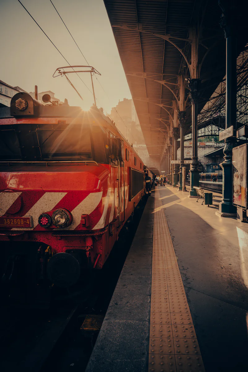 Red train at Porto station platform with warm sun rays streaming in (Punane rong Porto jaama platvormil, päikesekiired paistmas)