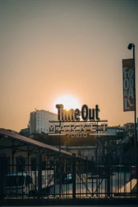 Time Out Market Porto sign silhouetted against bright sunset (Time Out Market Porto silt siluettina eredas päikeseloojangus)