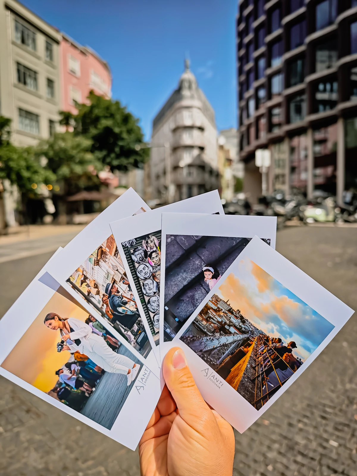 Hand holding travel postcards with Porto city buildings in background (Käsi hoiab postkaarte Porto linnavaate taustal)