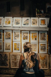 Girl observing a wall of hand-drawn urban sketch artworks at outdoor art market (Tüdruk uurib joonistuste seina tänavakunsti turul)