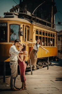 Iconic yellow Porto tram with people stepping out on a sunny street (Porto klassikaline kollane tramm liikumises)