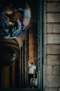Child looking up at suspended Earth globe inside historical building (Laps vaatab üles rippuva maakera poole ajaloolises hoones)