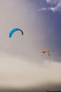 Two colorful kite surfers flying over hazy ocean sky (Kaks värvilist lohe Portos uduse taeva all)