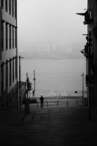 Silhouetted person descending stairs toward foggy waterfront in Porto (Isik laskub trepist uduse veeäärse suunas, mustvalge vaade Portos)