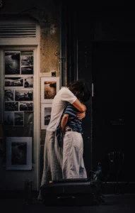 Couple embracing by a photo display Afonso Sereno on a dimly lit street (Soemeeleline hetk, jäädvustatud intiimsus avalikus ruumis)