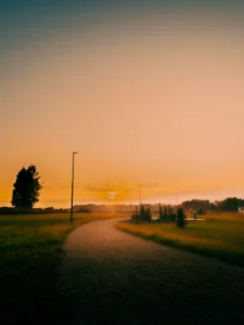 Curved country path with a single lamp post at sunset (Tühi ruum, valgus ja liikumissuund – vaoshoitud poeesia)