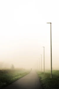 Foggy path with evenly spaced street lights and a lone walker (Kordus, tühjus ja inimese mikroolemus ruumis)