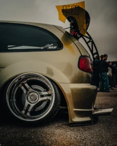 Golden car with lowered suspension and wide custom rim at Augustfest 2025 (Detailportree tuning-stiilis)