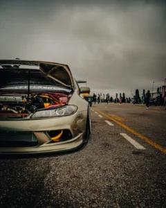 Golden sports car with open hood at Augustfest 2025, crowd in background (Näitusehetk, masinad ja publik)