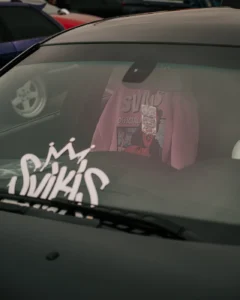 Windshield with “Swiks” decal at Augustfest 2025 car meet (Brändi või klubi detail auto klaasil)