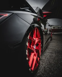 Close-up of red custom rim on black car at Augustfest 2025 (Detailne tuuningfoto, velgede fookus)