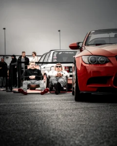 Red BMW and lineup of modified cars at Augustfest 2025 with spectators (Festivalimeeleolu, rahvahulk ja autokultuur)