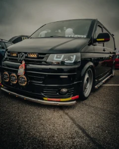 Modified black VW Transporter front view at Augustfest 2025 car festival (Stiilipuhas tuuning ja detailne dokumentatsioon)