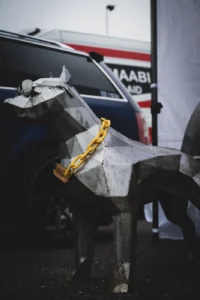 Metal dog sculpture with yellow chain around neck (Installatsiooni ja industriaalstiili segu)