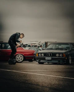 Man leaning over classic BMW at car meet (Autohuviliste hetk, keskendumine detailile)