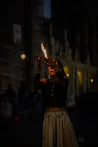 Woman doing fire dance tricks for audience during night street show in Porto