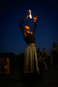 Female fire performer with flaming poi during street show in Porto