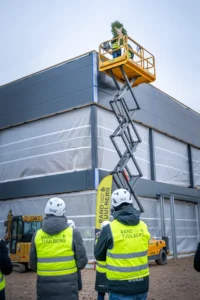 Kaks ehitajat tõstukil asetavad sarikapärga uue hoone katusele, tähistades sarikapidu.