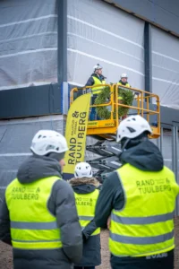 Kaks ehitajat tõstukil asetavad sarikapärga uue hoone katusele, tähistades sarikapidu.